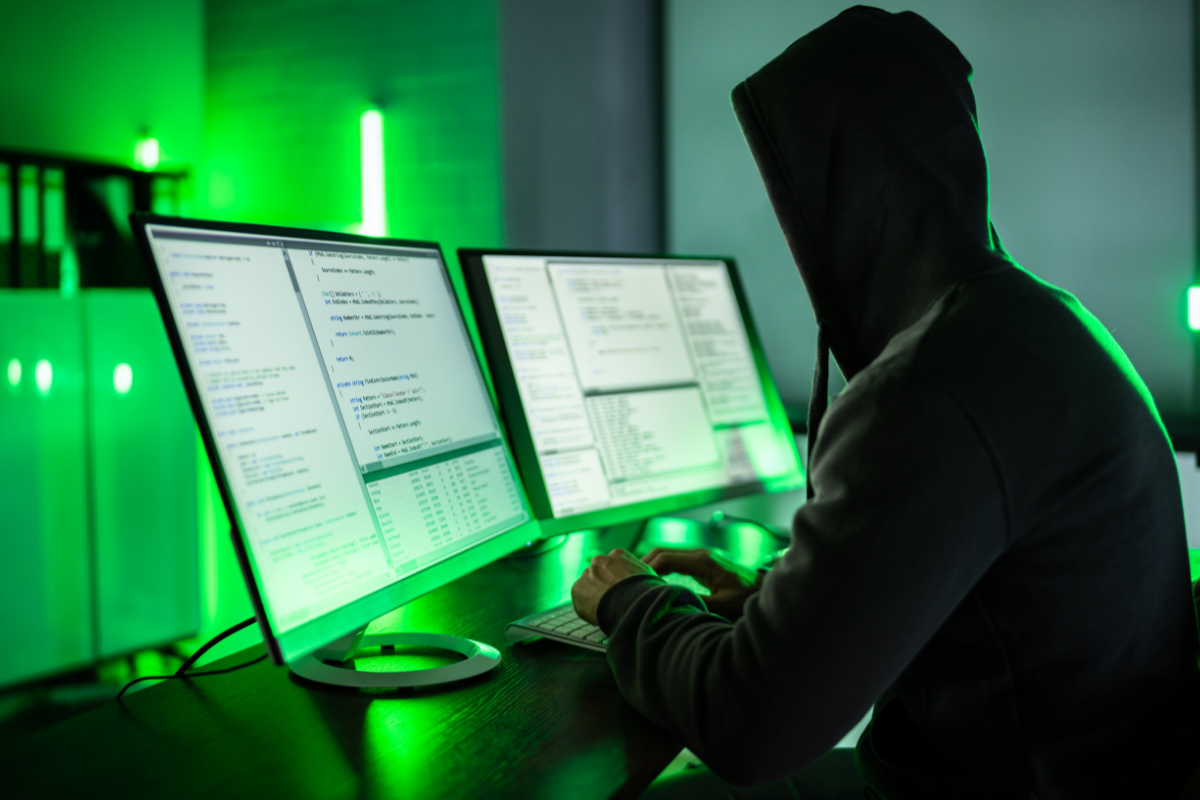 Hacker at computer with two monitors.