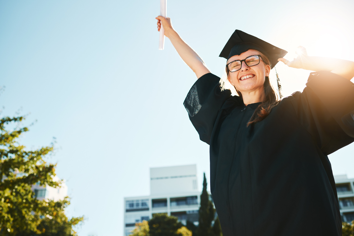 Girl in graduation outfit celebrating with diploma
