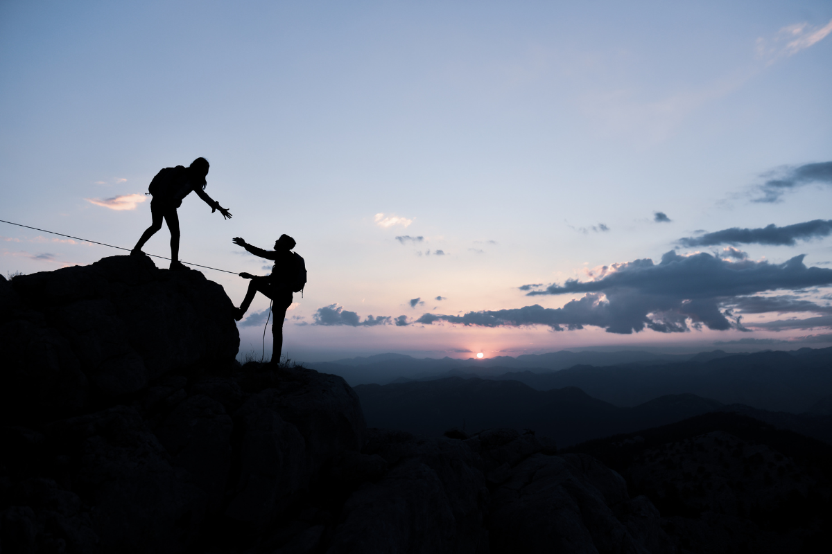 Woman helping man climb mountain