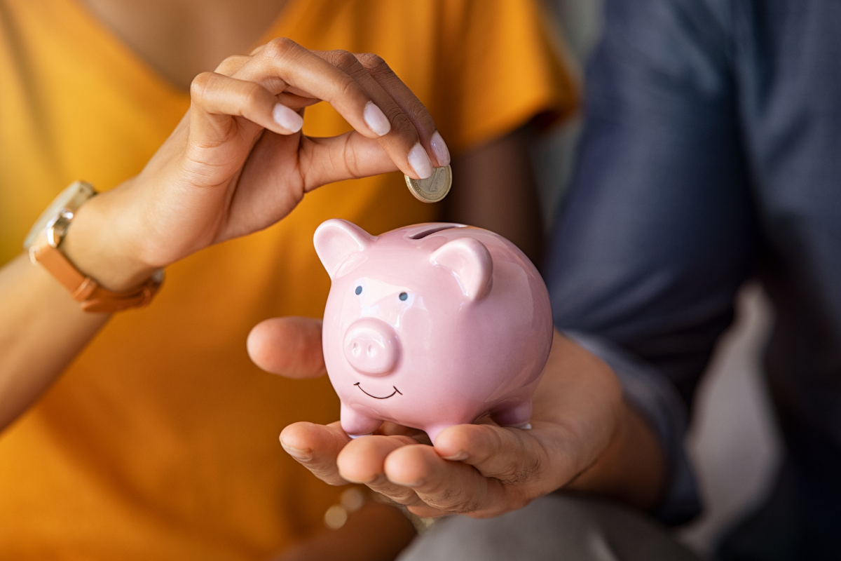 One person holding piggy bank, another person putting coin in piggy bank