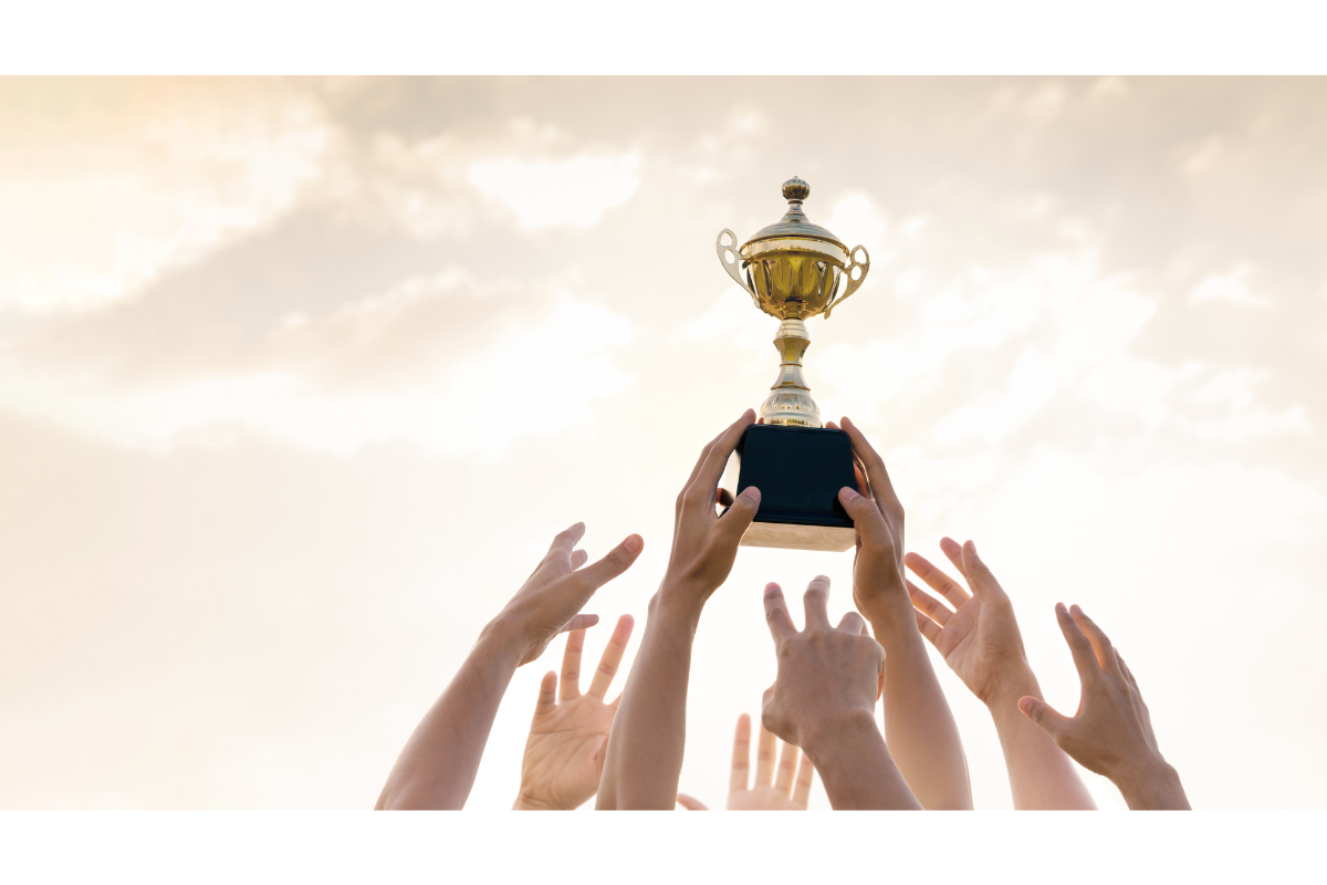 Multiple hands holding up a trophy