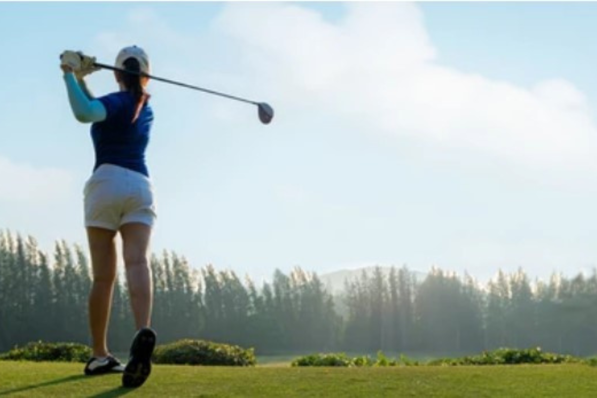woman teeing off on golf course