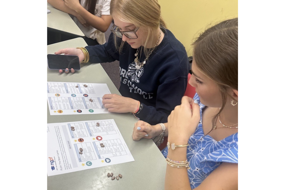 2 girls sitting at table looking at papers