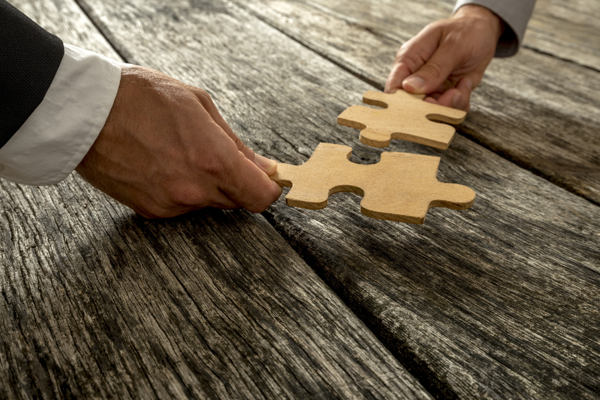 2 hands putting together puzzle pieces. partnership concept