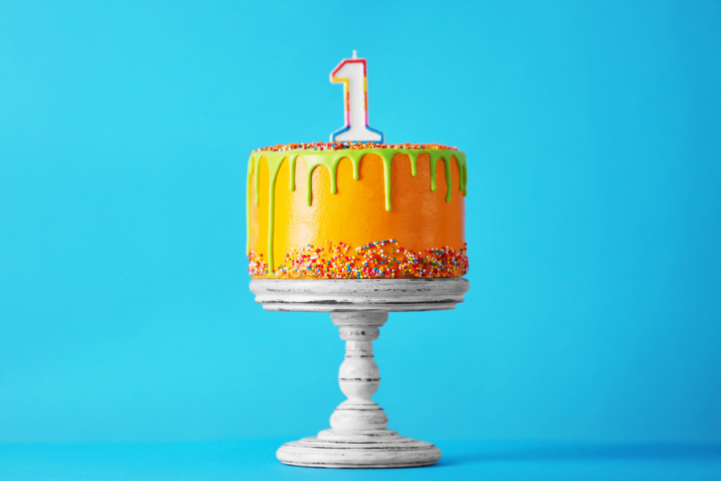 Birthday cake with one candle on blue background