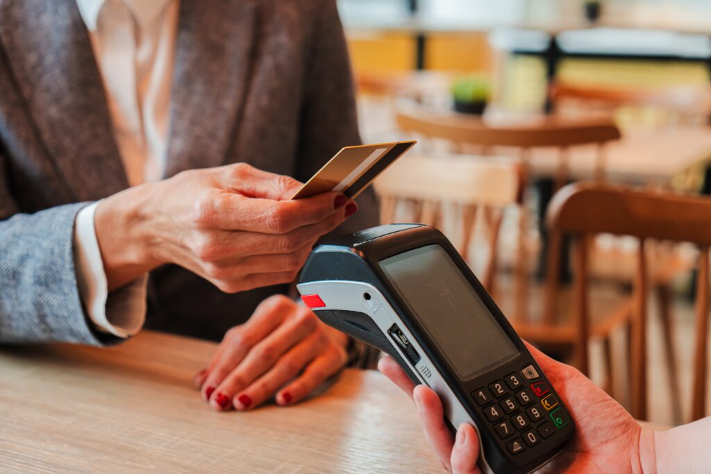 Person paying with a credit card, another person holding handheld payment device