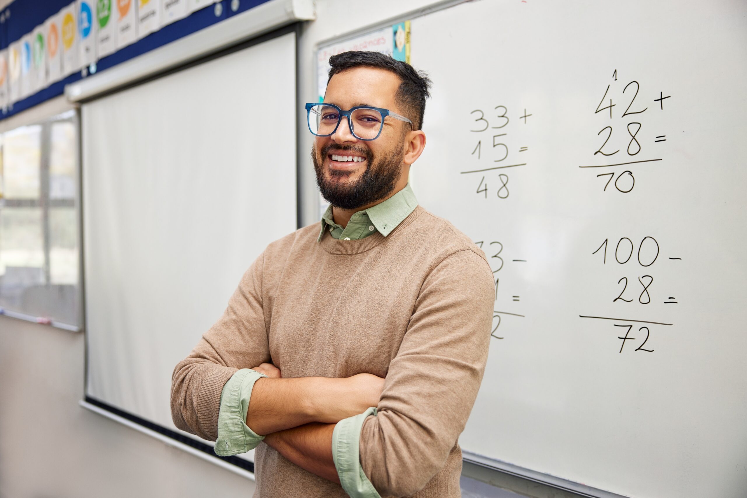 Teacher standing in front of whiteboard with equations written on it