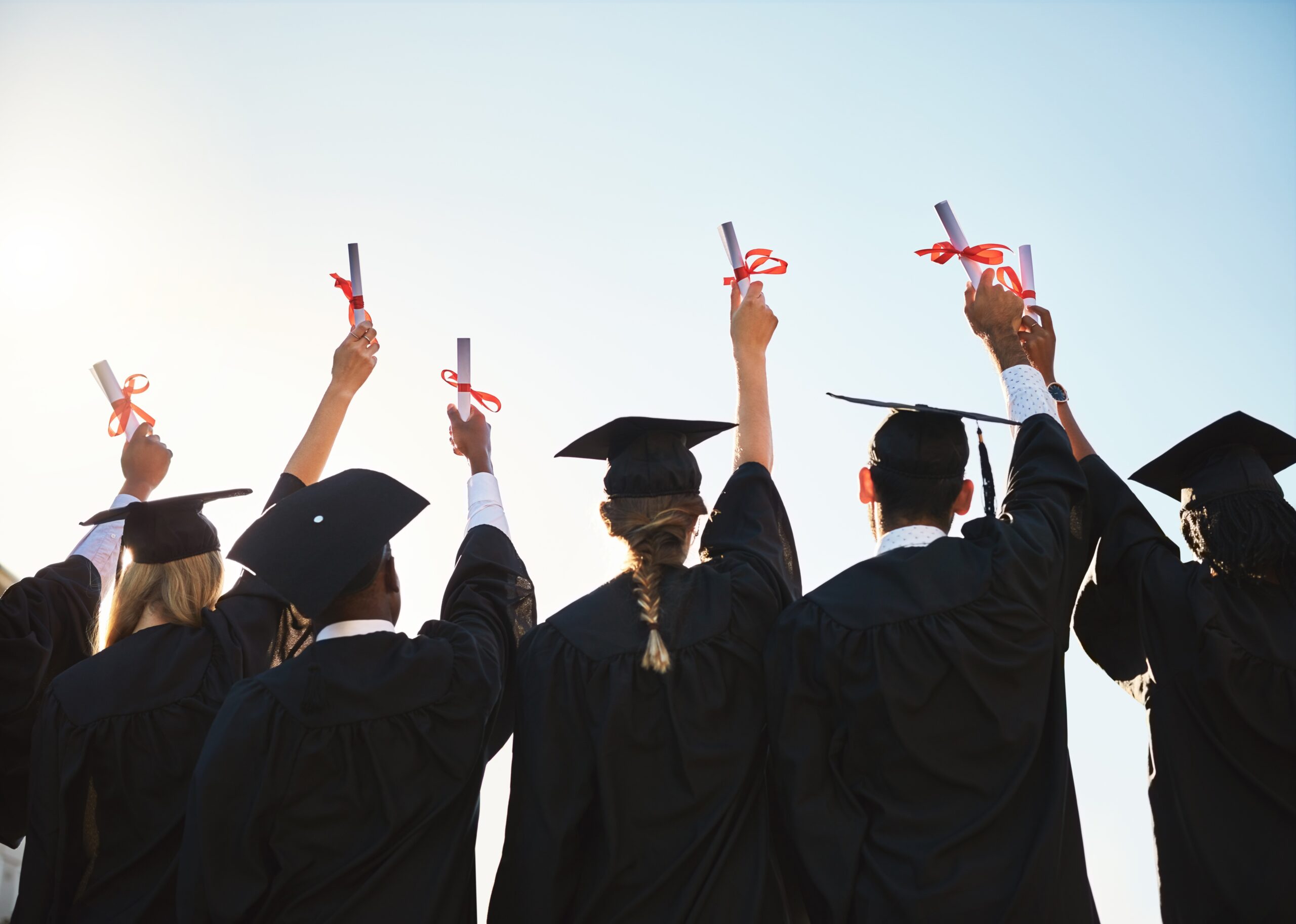 Students in graduation gowns holding diplomas