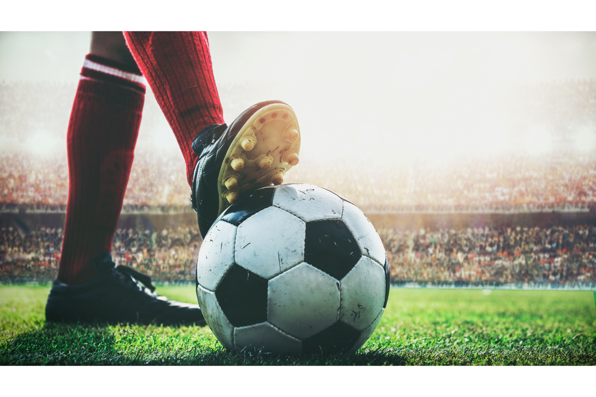 Soccer ball on field held in place by soccer player's cleat