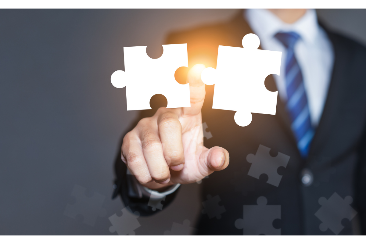 Businessman pointing finger at two puzzle pieces coming together