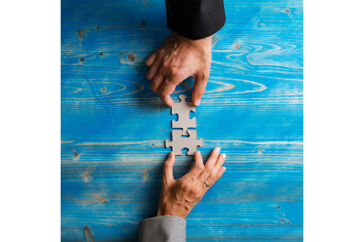 Two hands bringing two puzzle pieces together