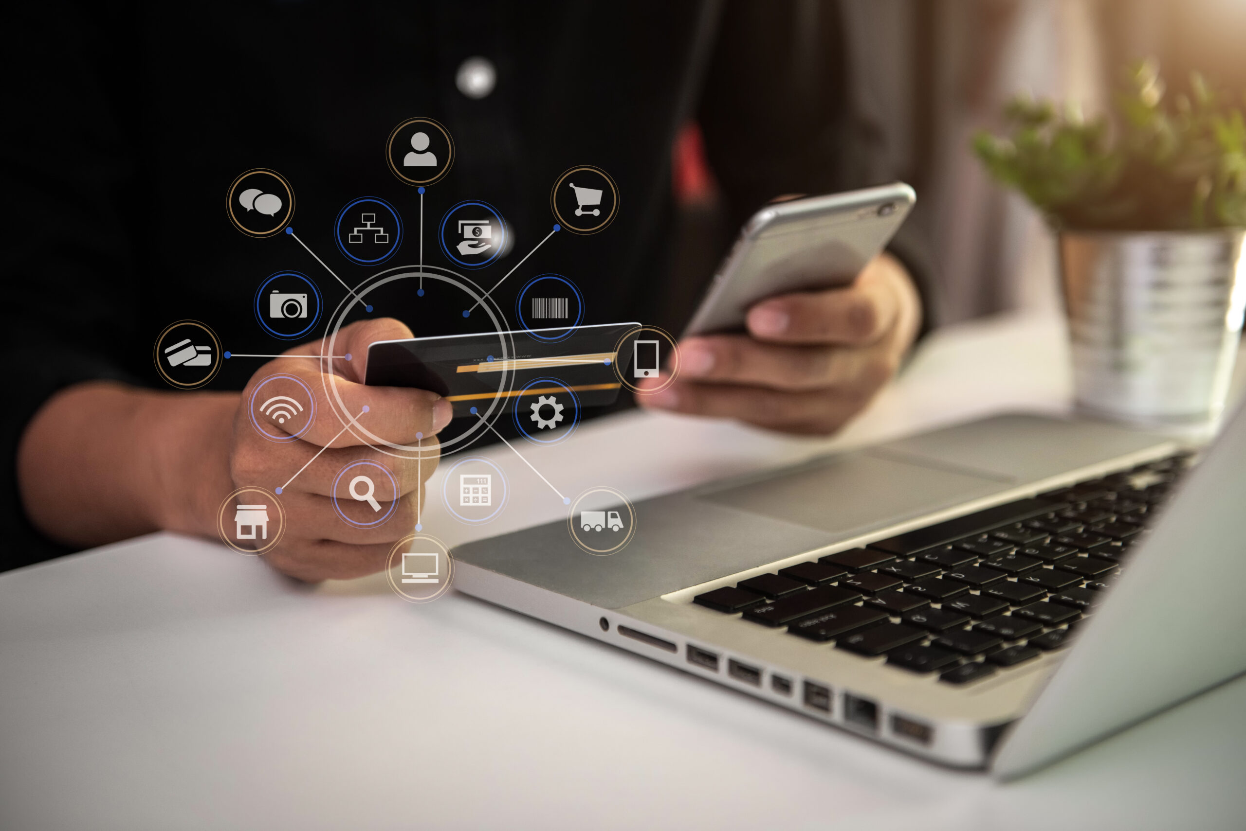 Person holding smartphone and credit card, laptop on table
