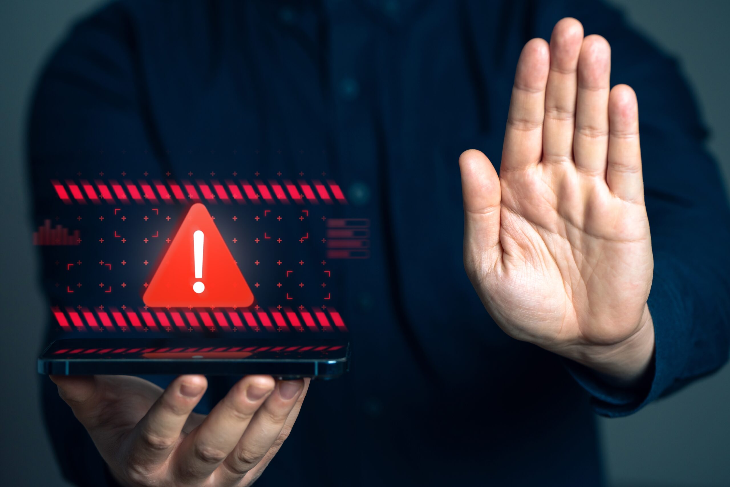 Person holding device and holding hand up, device showing warning