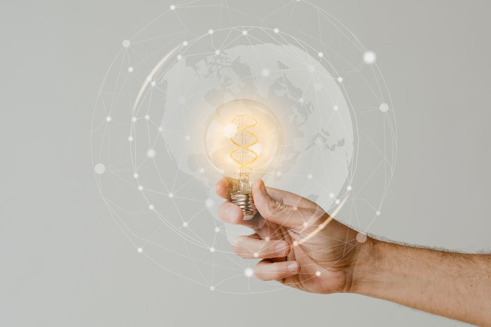 Person holding lightbulb; lightbulb within digital globe
