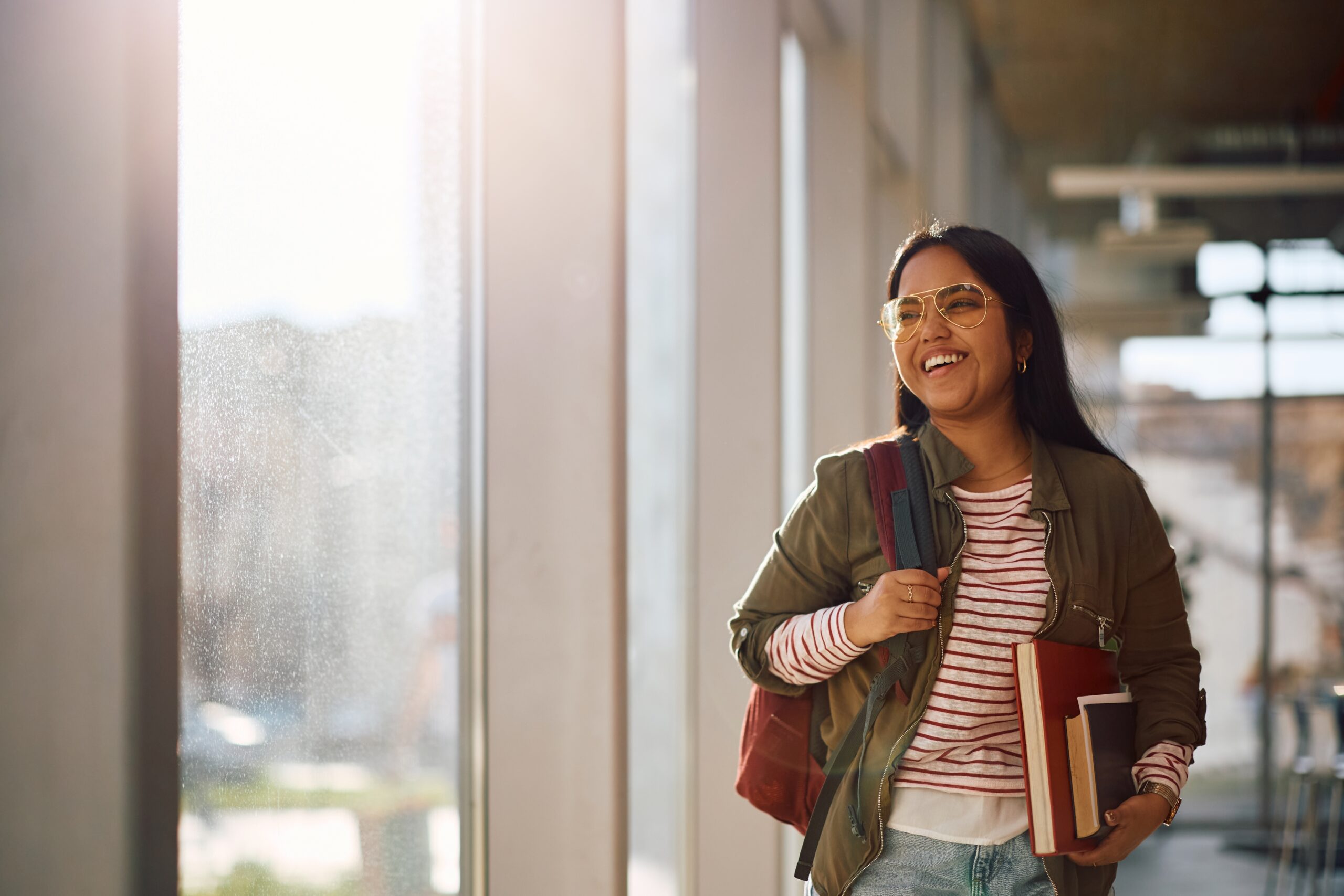 Female student walking through hall while carrying books