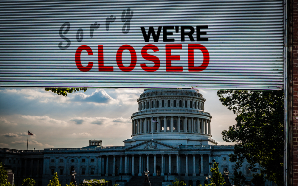 United States Capitol Building with blinds in front of the building; "Sorry, We're Closed" written on blinds