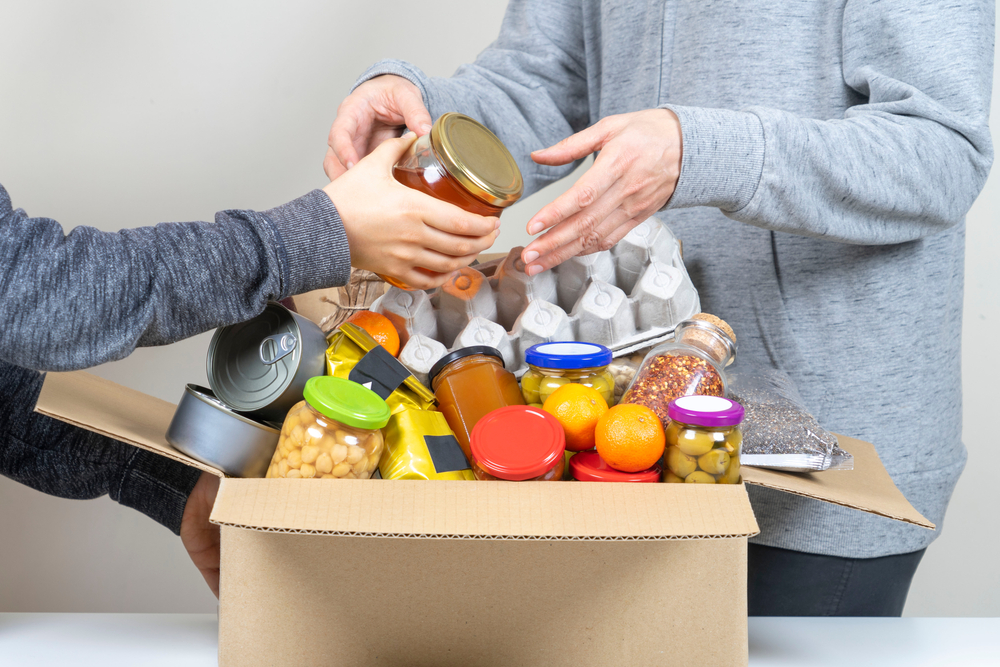 Volunteers putting various foodstuffs in cardboard box