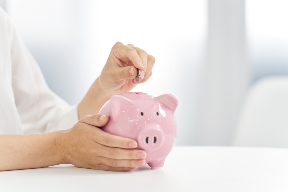 Person putting coin in piggy bank