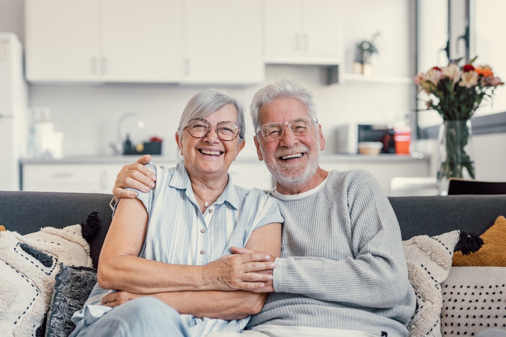 Senior couple smiling and hugging each other while sitting on a couch