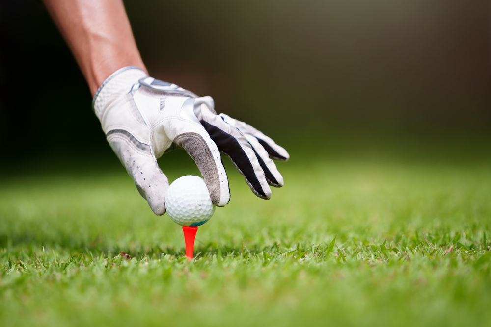 Golf player placing golf ball on tee