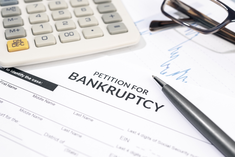 Bankruptcy petition form; calculator, pen, and glasses on top of bankruptcy form