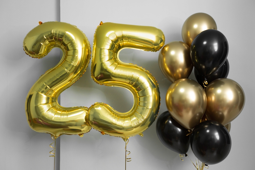 "25" made up of gold balloons, gold and black round balloons next to "25"