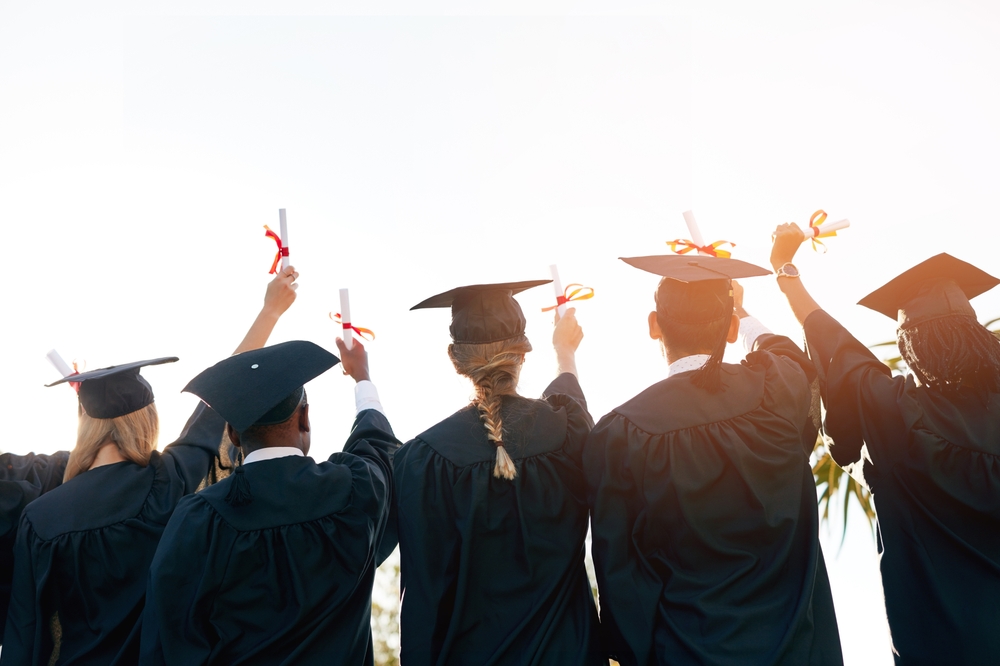 Graduating college students holding their diplomas in the air