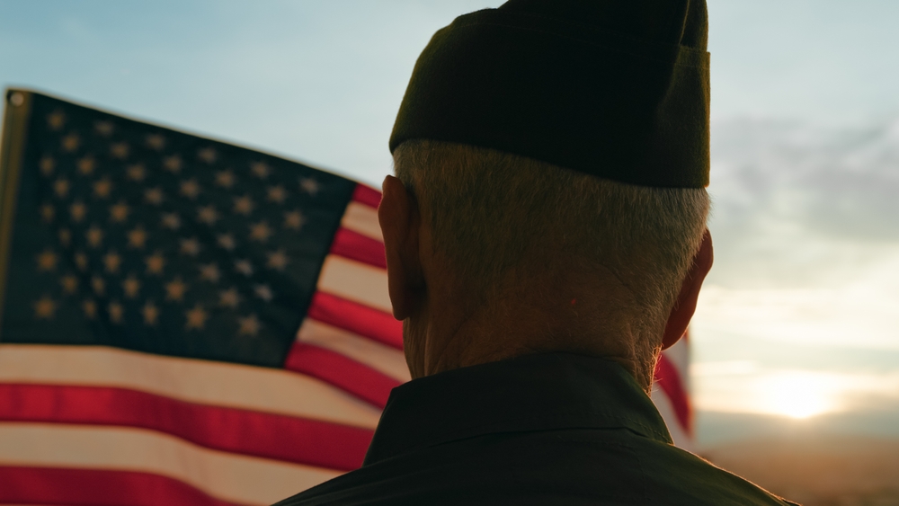 Elderly veteran standing in front of American flag