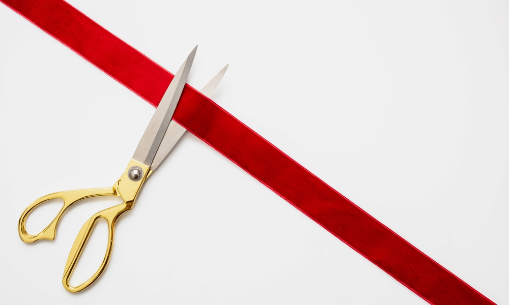 Gold scissors cutting red ribbon