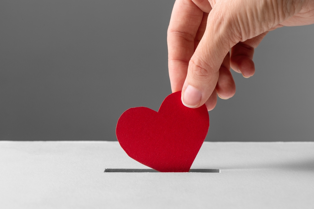 Person putting heart into slot on top of a box