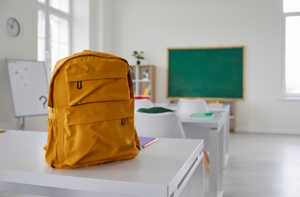 Backpack on top of desk in empty classroom