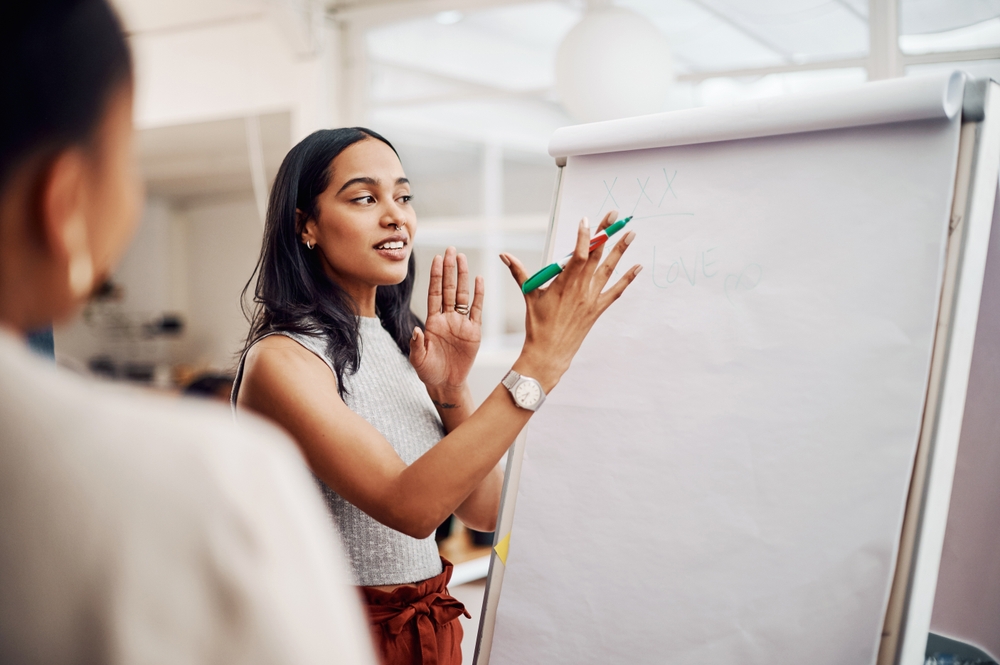 Woman in front of large notepad while holding green marker training employees