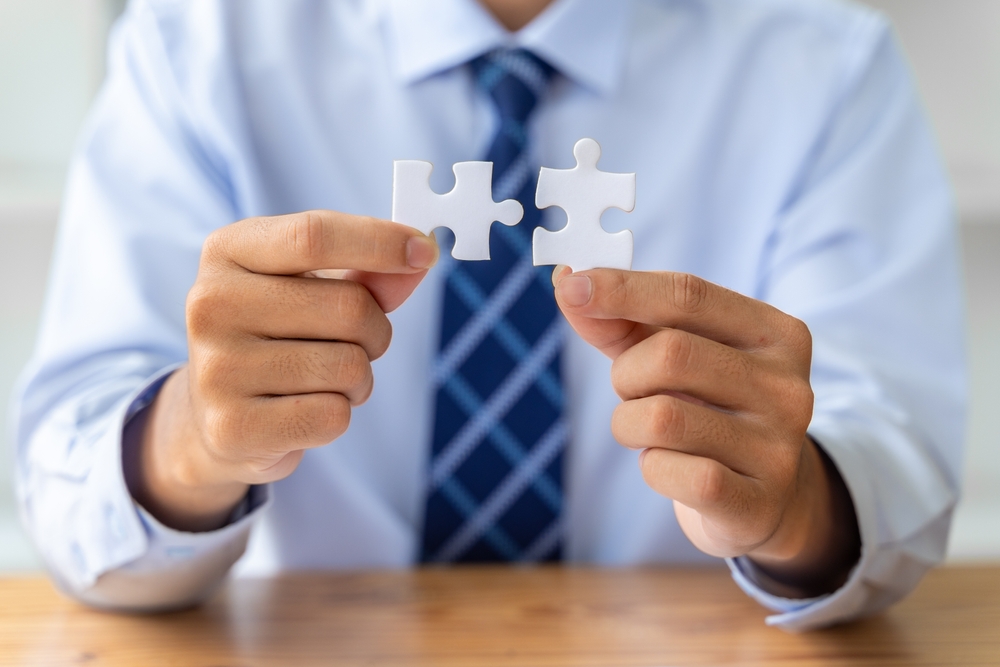 Businessman holding two puzzle pieces and bringing them together