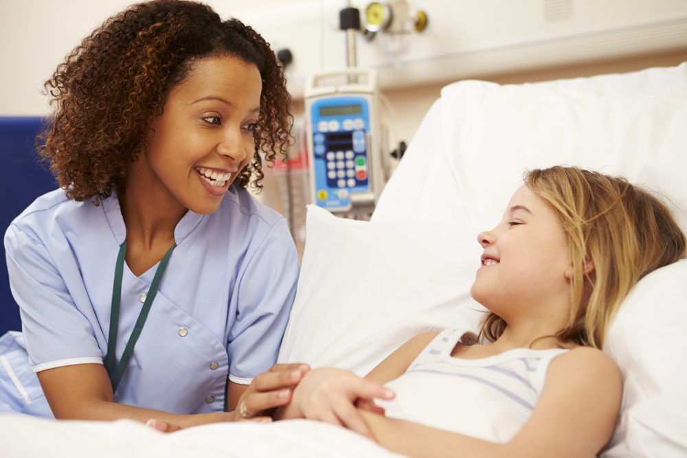 Nurse sitting and talking with young girl in hospital bed
