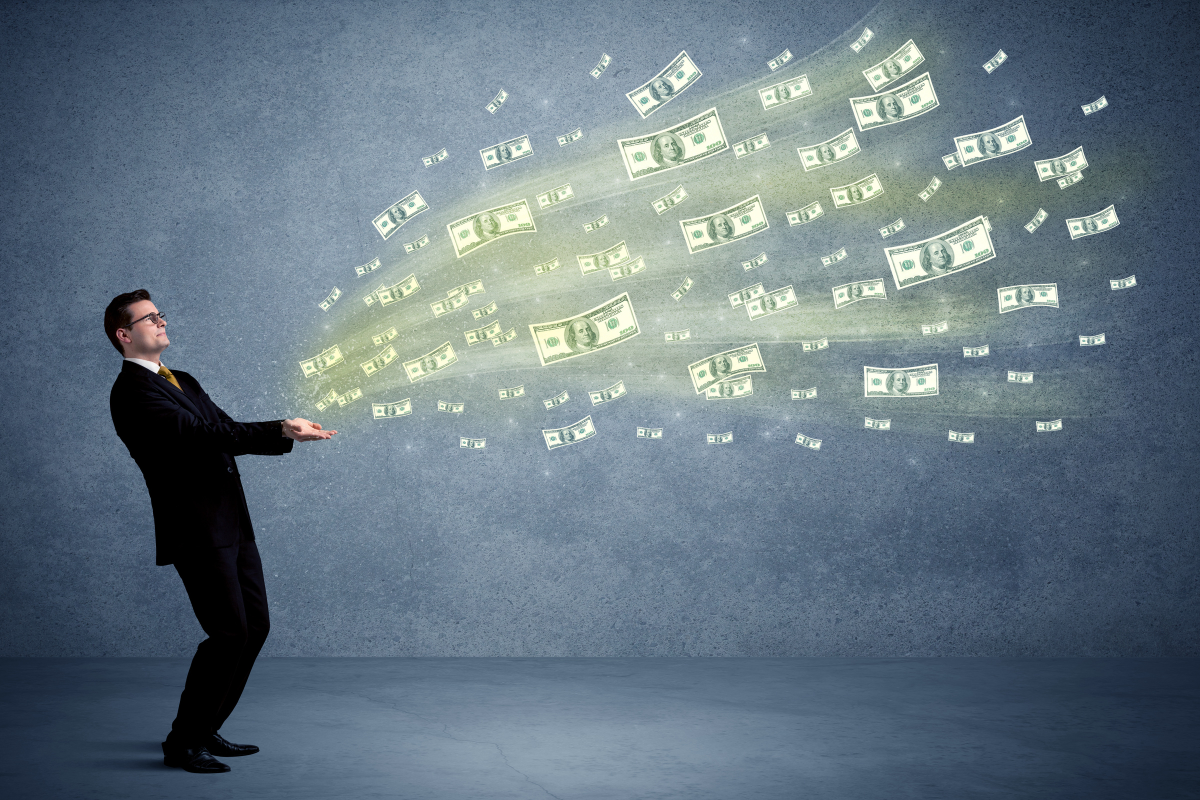 Caucasian male in business suit holding money,which flies through his hands