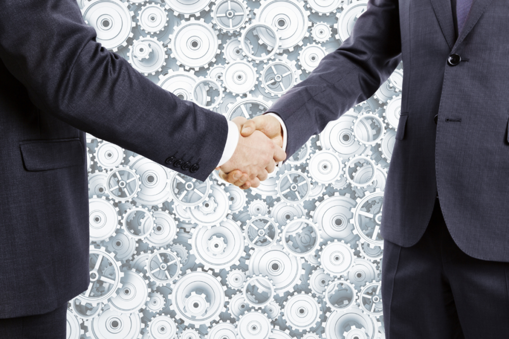 Businessmen shake hands at cogwheels background