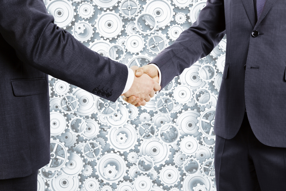 Businessmen shake hands at cogwheels background