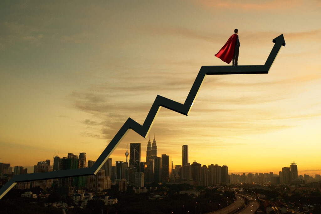 Businessman in suit and cape hero and charts with sunrise city skyline background . Financial economic growth concept