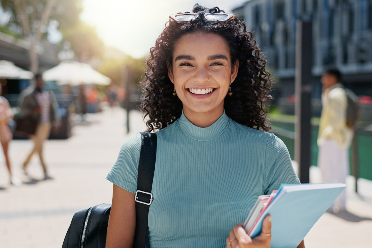 Woman, portrait and outdoor happiness at university, books for education or learning on campus. Female student, smile and notes for knowledge at college, academy scholarship for school in Canada