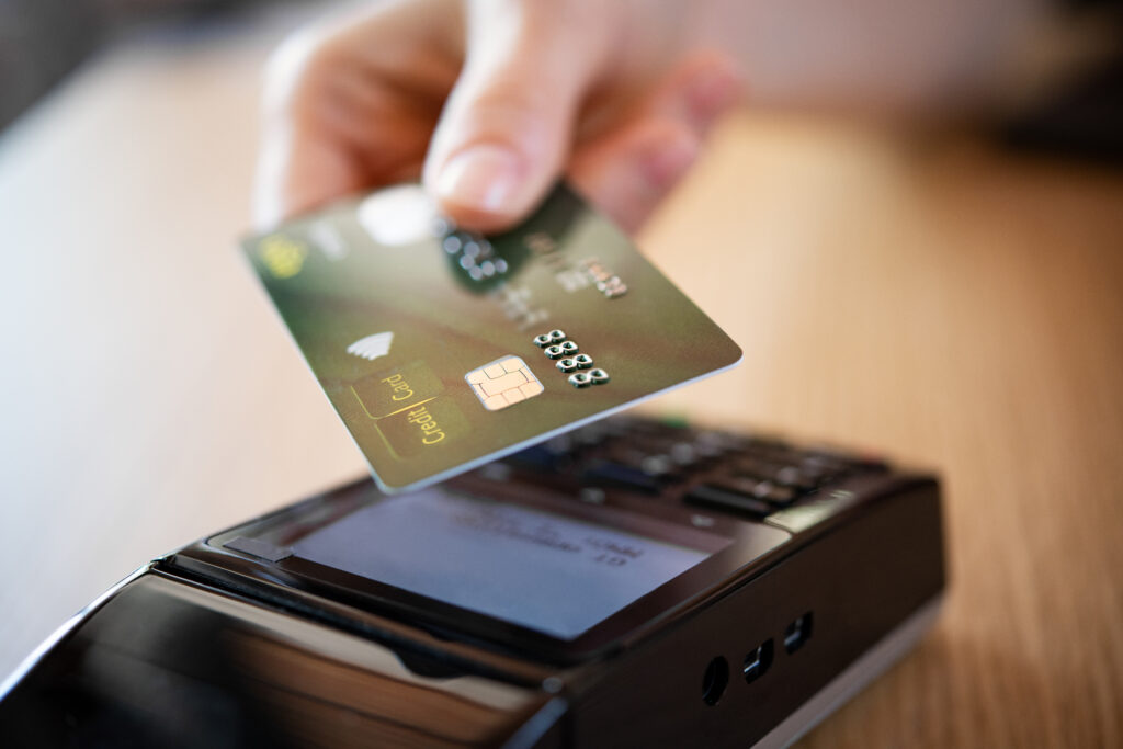 Close up hand of woman paying bill with credit card by contactless. Hand make payment with credit card with NFC technology on terminal device. Mobile payment at coffee shop with card reader machine.