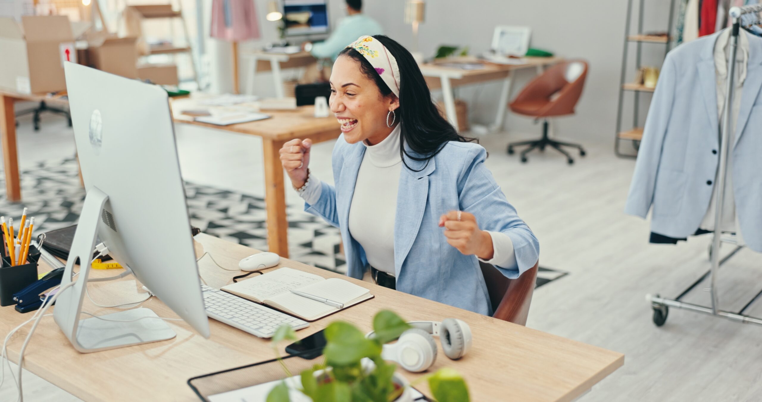 Small business, woman and fist on computer as fashion designer for good news and loan approval. Female person, entrepreneur and excited or happy for email notification at office for workshop funding