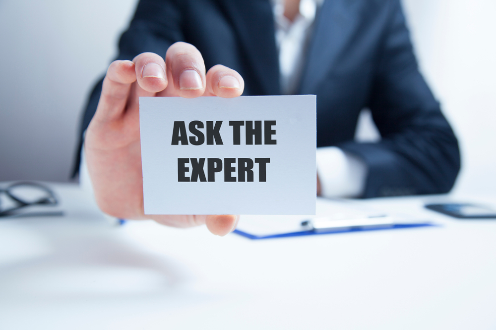 Businessman holding card; "Ask The Expert" written on card