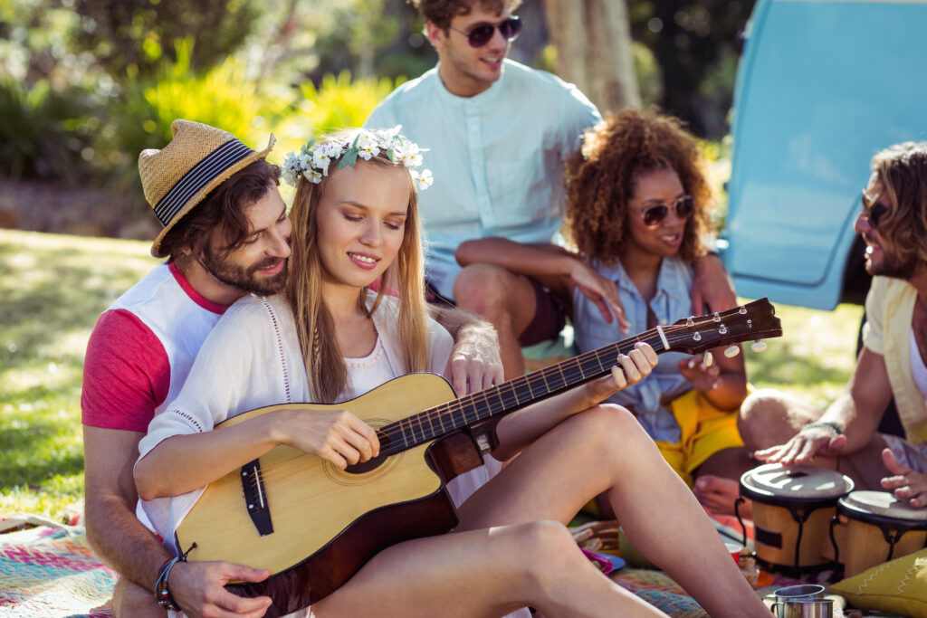 Group of friends having fun and playing music in park