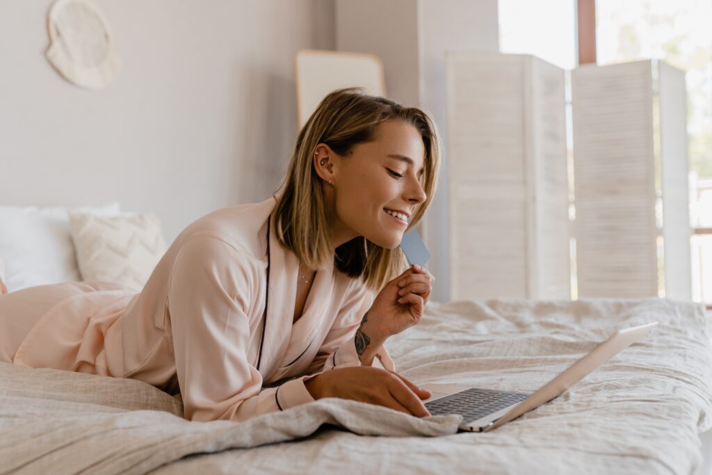 pretty smiling woman online on laptop at home on bed in pajamas