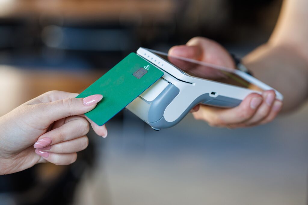 Closeup of a bank card tapping a wireless POS for secure cashless checkout, ideal for fintech, retail, SMB, and payment tech marketing.