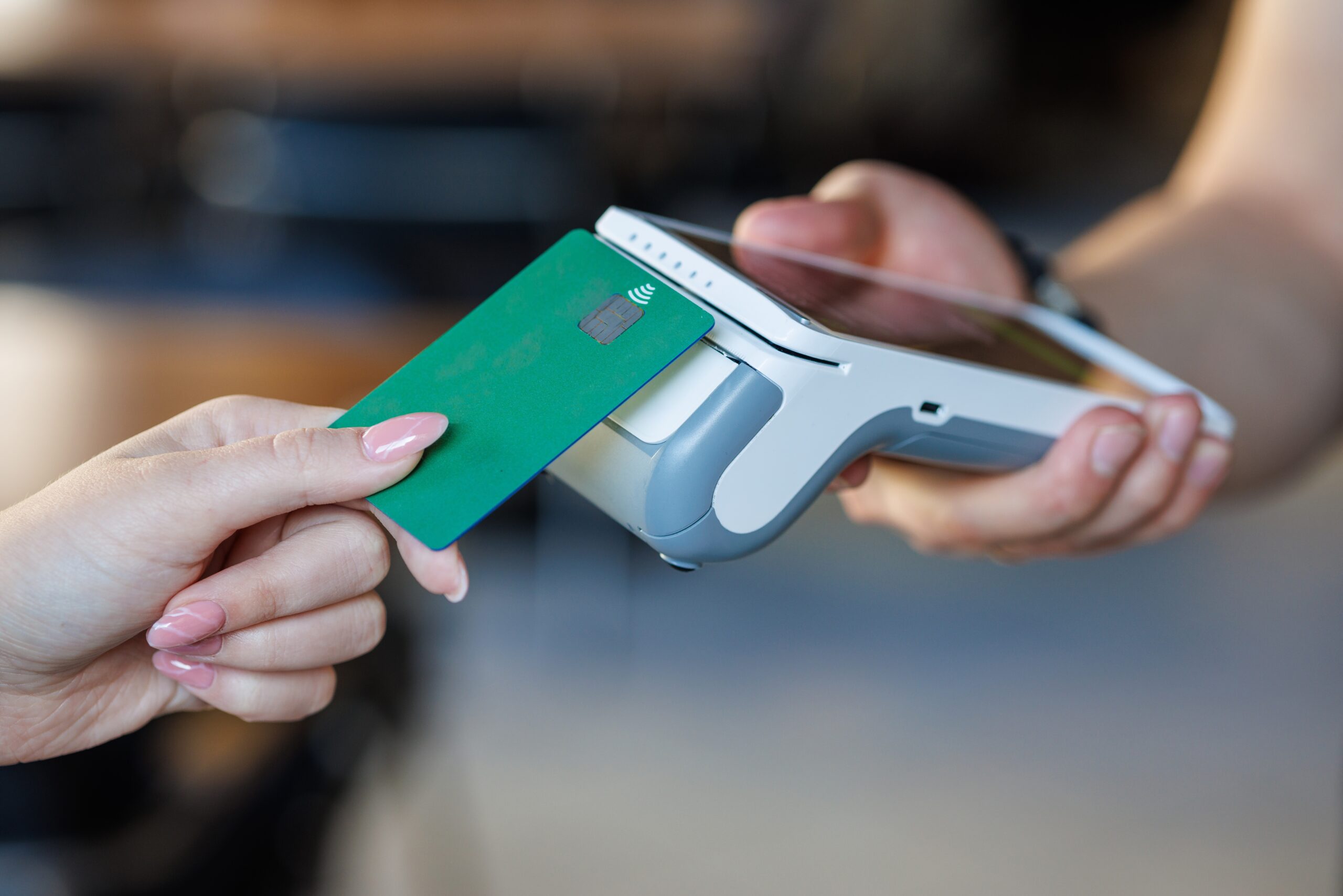 Closeup of a bank card tapping a wireless POS for secure cashless checkout, ideal for fintech, retail, SMB, and payment tech marketing.