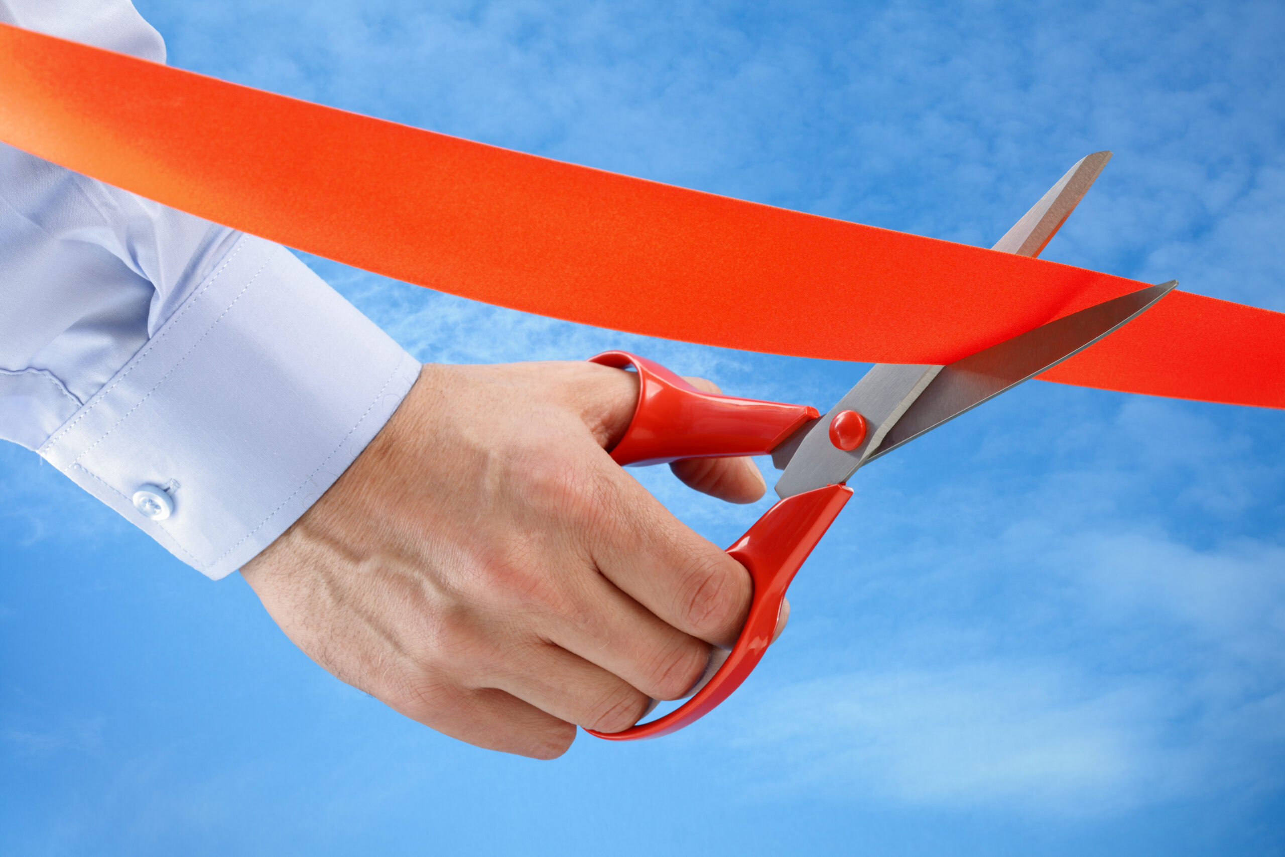 Businessman cutting a red ribbon with a pair of scissors