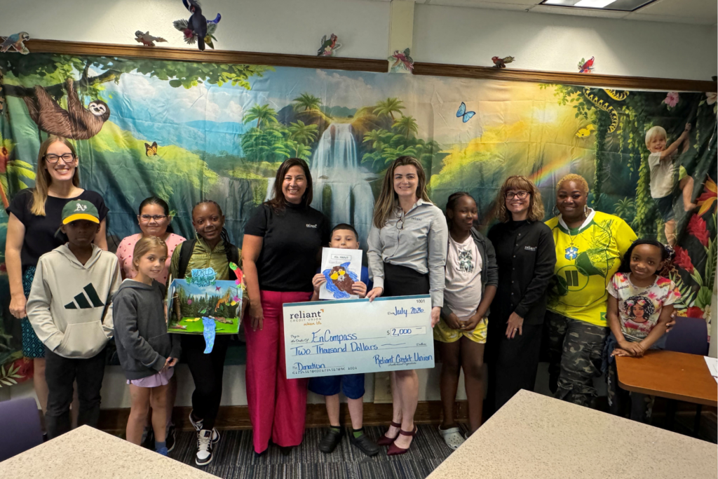 Representatives from Reliant Credit Union present a check to students and representatives from EnCompass at their Showcase of Learning.