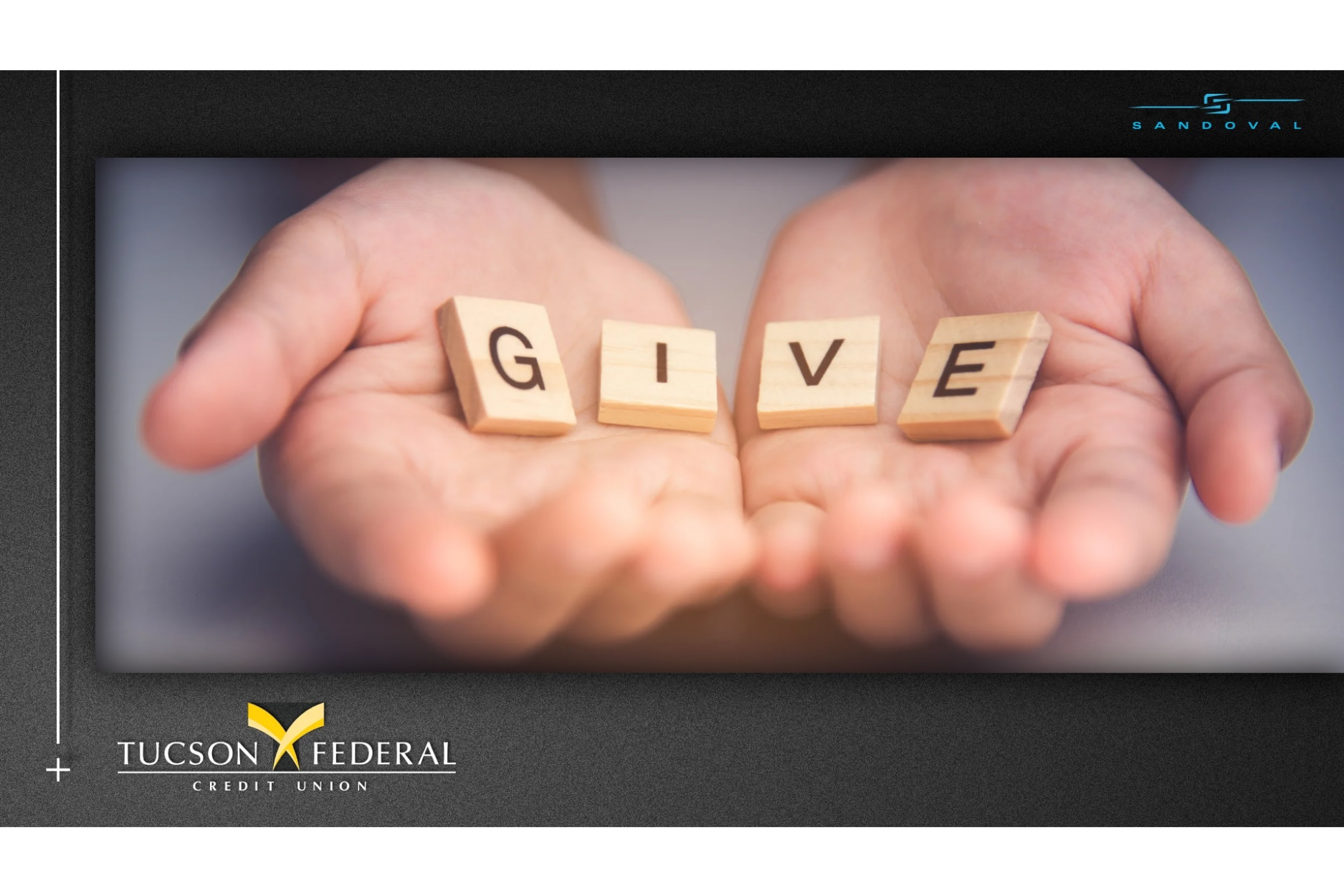 A charitable giving-themed graphic features a close-up of two open hands holding four wooden letter tiles that spell “GIVE.” The image is framed against a dark textured background, with the Tucson Federal Credit Union logo displayed in the lower-left corner and Sandoval branding in the upper-right. The simple imagery emphasizes generosity, giving back, charitable support, community involvement, philanthropy, and the credit union philosophy of helping others.