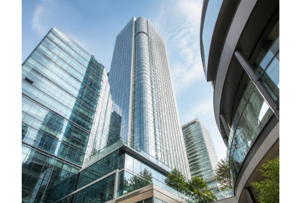 Photo realistic low-angle shot looking up at a modern commercial mixed-use skyline, with sleek glass towers, contemporary architecture, crisp daylight, and a strong upward perspective.